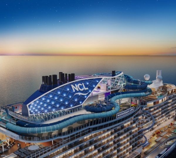 Norwegian Cruise Line Schiff mit Wasserrutschen und Poolbereich auf dem Oberdeck bei Sonnenuntergang.