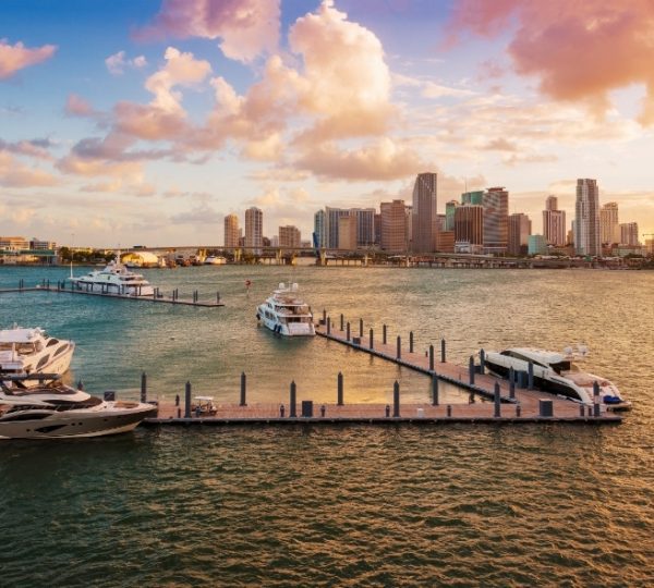 Hafen mit mehreren Yachten und der Skyline von Miami im Hintergrund bei Sonnenuntergang.